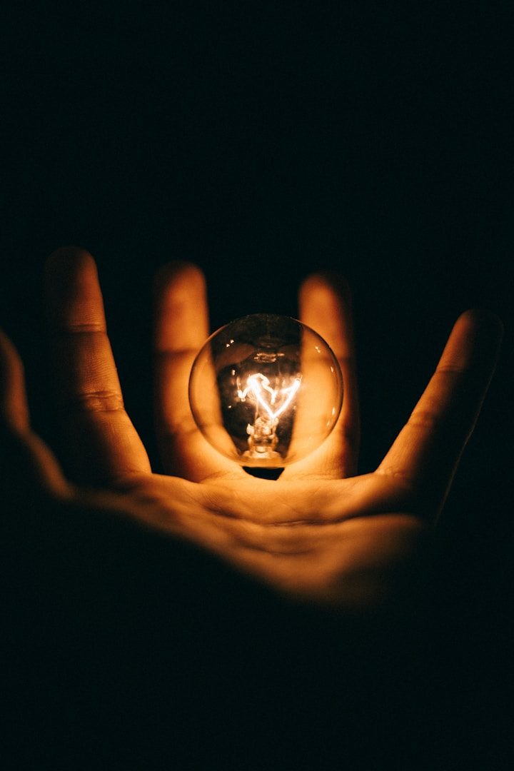 Lit light bulb hovering over outstretched human hand - signifying a "light bulb moment", i.e. the generation of an idea.